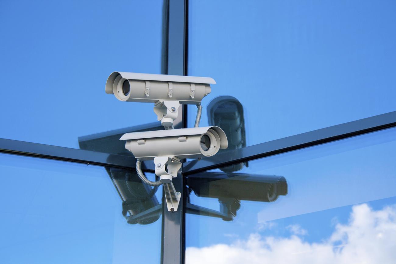 AI and CCTV surveillance: An illustration of a security camera with a facial recognition algorithm and a human face with different emotions.